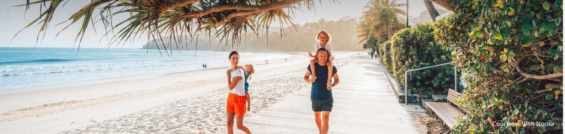 Family Walking on Noosa Main Beach Esplanade A family enjoying a scenic walk along the beachfront boardwalk and esplanade at Noosa Main Beach, located just 4km from Cayman Quays.