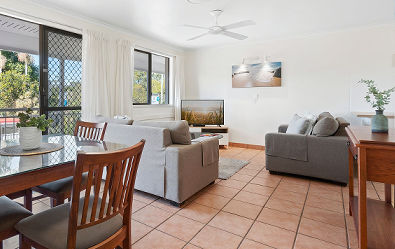 Standard Self-Contained Apartment Living Area Budget-friendly Standard Apartment interior at Cayman Quays featuring a self-contained lounge zone, big screen television, and dedicated dining area.